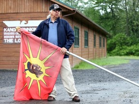 Kenneth Deer, poses with a flag outside a longhouse in Kahnawake, Quebec, June 2, 2015.