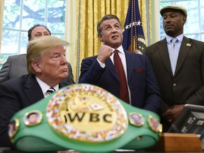 President Donald Trump, left, and heavyweight champion boxer, Lennox Lewis, right, watch as Sylvester Stallone gestures in the Oval Office of the White House in Washington, Thursday, May 24, 2018, where Trump granted a posthumous pardon to Jack Johnson, boxing's first black heavyweight champion.