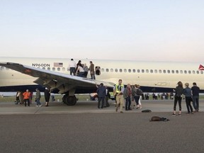 Passengers exit a plane and stand on the tarmac of Denver International Airport after being evacuated from a Delta flight from Detroit on Tuesday May 8, 2018, in Denver. A Delta Air Lines flight with 153 people on board was evacuated at Denver's airport after passengers reported smoke in the cabin. (Rachel Naftel via AP)