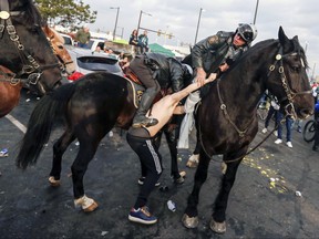 In this Jan. 21, 2018, file photo, a fan is taken into custody after violence erupted in parking lot M as Philadelphia Police Department officers and Pennsylvania State Police troopers on horseback tried to disperse fans who were tailgating, hours before the Philadelphia Eagles were scheduled to host the Minnesota Vikings in the NFC championship NFL football game in Philadelphia. Andrew Tornetta, a Philadelphia Eagles fan accused of punching a police horse and a mounted officer before the Eagles' NFC championship victory, filed a lawsuit against the team and police Wednesday, May 30, maintaining he didn't strike the horse and alleging assault and battery by the police, claiming he was beaten for no reason. (Andrew Mills/The Star-Ledger via AP, File)