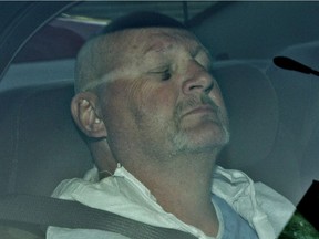 Richard Henry Bain sits with his eyes closed in the back of a police car, as he arrives at the Montreal courthouse in Montreal, Thursday September 6, 2012.