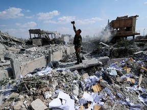 A Syrian soldier films the damage of the Syrian Scientific Research Center which was attacked by U.S., British and French military strikes to punish President Bashar Assad for suspected chemical attack against civilians, in Barzeh, near Damascus, Syria on Saturday, April 14, 2018. (AP Photo/Hassan Ammar)