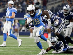 Los Angeles Chargers running back Melvin Gordon (28) escapes tackle attempt by Dallas Cowboys' DeMarcus Lawrence (90) and Anthony Brown (30) late in the second half of an NFL football game, Nov. 23, 2017, in Arlington, Texas.