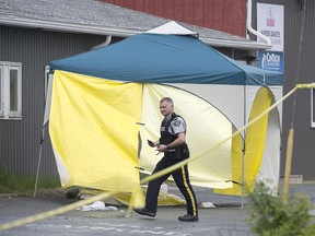 An RCMP officer walks past a makeshift tent covering a body at a shooting which left one person dead in Dartmouth, N.S., on Saturday, May 26, 2018.