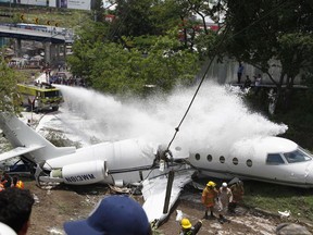 A fire truck sprays with foam a white Gulfstream jet that appears broken in half near the centre, in Tegucigalpa, Honduras, Tuesday, May 22, 2018.