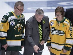 Humboldt Broncos team president Kevin Garinger, centre, and Humboldt Broncos athletic therapist Dayna Brons's mom Carol Brons as dad Lyle take part in a ceremonial puck drop before the Memorial Cup semifinal in Regina on Friday, May, 25, 2018. (THE CANADIAN PRESS/Jonathan Hayward)