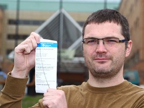 Chris Martin holds up the parking ticket he received shortly after he and his wife arrived at Alberta Children's Hospital with their sick baby. The hospital forgave the ticket. Martin is photographed on May 9, 2018 at Peter Lougheed Hospital, where his son is being treated.