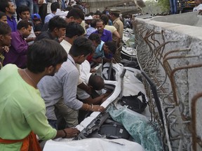 People look for survivors inside vehicles crushed when a section of an under construction overpass collapsed in Varanasi, India, Tuesday, May 15, 2018. At least a dozen people were reported to be killed in the accident. (AP Photo)