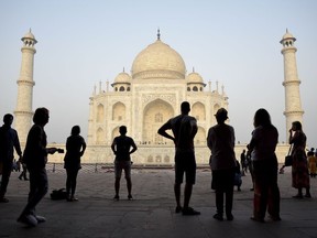 FILE - In this March 22, 2018 file photo, tourists visit India's famed monument of love, the Taj Mahal, in Agra, India. The Taj Mahal, that shining white monument to love, is turning a little green and yellow because of air pollution and swarms of insects, and India's Supreme Court is not pleased. The court has ordered officials to create a plan to ensure the Taj Mahal is properly cared for, and report back by Wednesday, May 9. While officials are cleaning the Taj's exterior with a special clay, the lawyer who brought the case to the court says not enough is being done.
