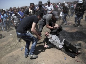 An elderly Palestinian man falls on the ground after being shot by Israeli troops during a deadly protest at the Gaza Strip's border with Israel, east of Khan Younis, Gaza Strip, Monday, May 14, 2018. Thousands of Palestinians are protesting near Gaza's border with Israel, as Israel celebrates the inauguration of a new U.S. Embassy in contested Jerusalem.
