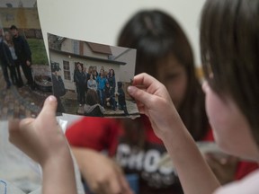 Lora Cardinal looks at family photos that include her father, Tyler Applegate, at a home in Saskatoon on May 15, 2018. Applegate was shot in his front yard in July 2017 and passed away from his injuries the following month, becoming the city's third homicide victim of 2017. Two men have now been charged with manslaughter in connection with his death.