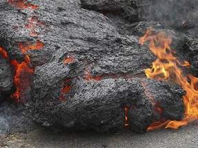 Lava burns across a road in the Leilani Estates subdivision on Saturday, May 5, 2018, near Pahoa, Hawaii. (AP Photo/Caleb Jones)