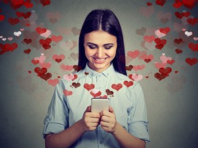 Beautiful happy woman sending love text message on mobile phone with red hearts flying away
