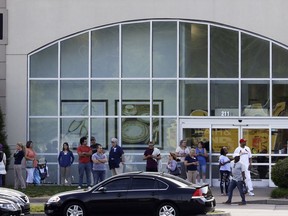 People stand outside a store at Opry Mills mall Thursday, May 3, 2018, in Nashville, Tenn. Nashville police said a suspect was taken into custody after a person was shot inside the mall. The mall was evacuated after the gunfire was reported. One person was taken to a hospital and was reported to be in critical condition.