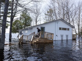 A man carries a bag of clothing before leaving his home as floodwaters from the Saint John River continue rising in Grand Lake, N.B. on Wednesday, May 2, 2018.