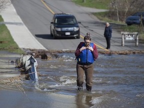 A Saint John, N.B. woman watches her step as she wades across a flooded road to get to work on Saturday, May 5, 2018.
