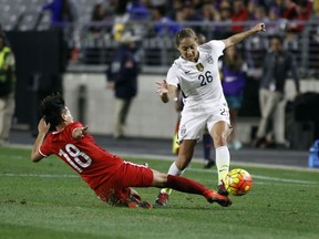 In this Dec. 13, 2015, file photo, China's Han Peng (18) slides in to knock the ball away from United States' Jaelene Hinkle during an international friendly soccer match, in Glendale, Ariz.