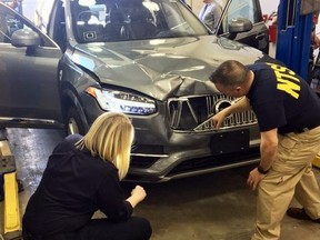 In this March 20, 2018, file photo provided by the National Transportation Safety Board, investigators examine a driverless Uber SUV that fatally struck a woman in Tempe, Ariz.