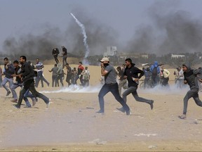Palestinian protesters run for cover from teargas fired by Israeli troops near the border fence, east of Khan Younis, in the Gaza Strip, Tuesday, May 15, 2018.
