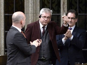 NDP MP Charlie Angus holds a feather as he rises to vote in favour of the NDP's motion calling on the House of Commons to officially ask the Pope to apologize to residential school survivors, on Parliament Hill in Ottawa on Tuesday, May 1, 2018.