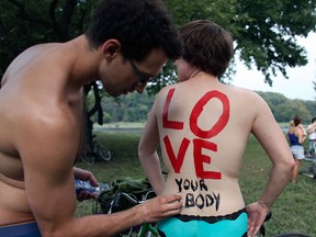 In this Sunday, Sept. 4, 2011, file photo, Cheryl Rehmann has a message painted on her back by Matthew Wellstein before the start of the naked bike ride in Philadelphia.