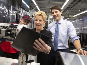Prime Minister Justin Trudeau and Ontario Premier Kathleen Wynne laugh while trying their hand at leather stitching with instructor Kyle McCaig during their visit to the TMMC Toyota Manufacturing facility in Cambridge, ON on Friday, May 4, 2018.