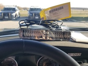 Police lights are seen on the dashboard of a vehicle.