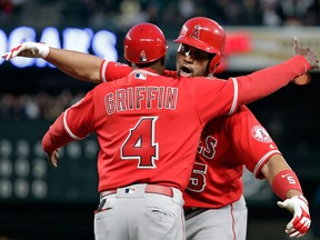 Los Angeles Angels' Albert Pujols, right, embraces first base coach Alfredo Griffin after hitting a single against the Seattle Mariners in the fifth inning of a baseball game on May 4, 2018