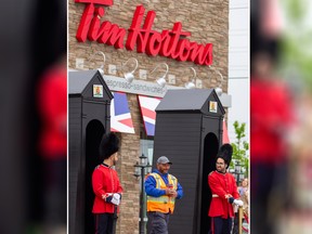 A man walks past the "Tim's Guards" in front of a Tim Hortons in London, Ont., where fans of the royals came to watch the wedding of Meghan Markle and Prince Harry, the Duke and Duchess of Sussex, on Saturday, May 19, 2018. THE CANADIAN PRESS/ Geoff Robins