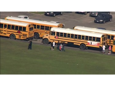 In this image taken from video a police officer walks near school buses as law enforcement officers respond to a high school near Houston after an active shooter was reported on campus, Friday, May 18, 2018, in Santa Fe, Texas.