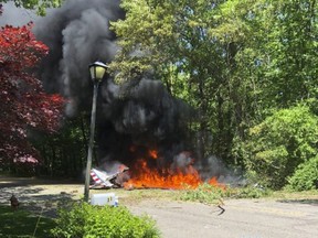 This photo provided by Lauren Peller shows a small airplane that crashed in Melville, N.Y., Wednesday, May 30, 2018. The small vintage airplane that was part of a GEICO stunt team of five other planes crashed in the wooded residential area on Long Island, killing its pilot, Suffolk County police said Wednesday. (Lauren Peller via AP)
