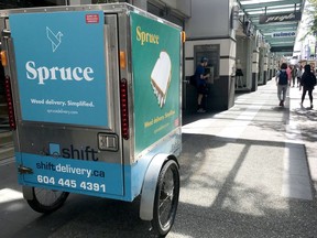A bike courier advertising Spruce Weed Delivery makes a stop at a Granville St. condominium in Vancouver.