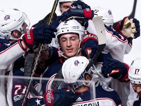 Columbus Blue Jackets' Zach Werenski is surrounded by teammates after scoring the winning goal past Montreal Canadiens goalie Charlie Lindgren during overtime in NHL hockey action on Nov. 14, 2017