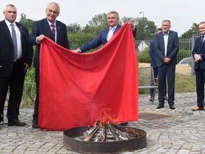 Czech President Milos Zeman (2ndL) and Chancellor of the Office of the President Vratislav Mynar (C) burn a large piece of red textile, which refers to an oversized red underwear that was one of the symbols of political opponents, during its ritual burning on June 14, 2018 at the Prague Castle in the Czech capital. (Michal Cizek/Getty Images)