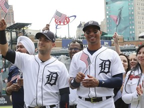 Detroit Tigers shortstop Jose Iglesias, left, and center fielder Leonys Martin wave an American flag after participating in a naturalization ceremony before a baseball game, Monday, June 25, 2018, in Detroit.