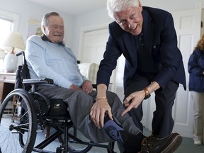 Former President Bill Clinton jokes with former President George H.W. Bush as Bush shows off a pair of "Bill Clinton socks," while Clinton visits Bush at his home in Kennebunkport, Maine, Monday, June 25, 2018. (Evan F. Sisley/Office of George Bush via AP)