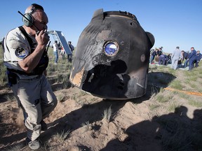 A NASA employee speaks on the phone next to the Russian Soyuz MS-07 space capsule shortly after landing about 150 km (90 miles) south-east of the Kazakh town of Dzhezkazgan, on June 3, 2018.
