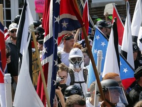 In this Saturday, Aug. 12, 2017, photo white nationalist demonstrators walk into the entrance of Lee Park surrounded by counter demonstrators in Charlottesville, Va.