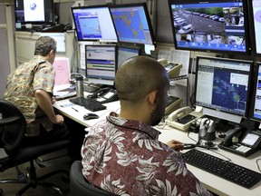 Hawaii Emergency Management Agency officials work at the department's command centre in Honolulu on Friday, Dec. 1, 2017. (AP Photo/Caleb Jones)