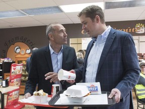 Conservative Leader Andrew Scheer, right, and Saguenay-Le Fjord candidate Richard Martel chat as they carry food at the famous Boivin cheese counter, Thursday, June 14, 2018 in Saguenay, Que. The Conservatives appear poised to steal a Quebec riding away from Justin Trudeau's ruling Liberals. Conservative candidate Martel has jumped into a commanding early lead in a federal byelection being held in the riding of Chicoutimi-Le Fjord.THE CANADIAN PRESS/Jacques Boissinot