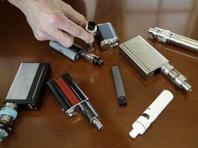 FILE - In this Tuesday, April 10, 2018 file photo, a high school principal displays vaping devices that were confiscated from students in such places as restrooms or hallways at the school in Massachusetts. A government study released on Thursday, June 7, 2018, said teen vaping seemed to hold steady in 2017 and cigarette smoking continued to decline _ a promising sign of progress against a wide range of nicotine and tobacco products. However, some experts were cautious about the results. They noted the survey did not asks specifically about Juuls, a wildly popular form of e-cigarettes.
