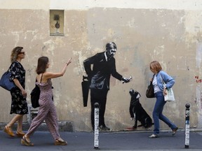 People walk past a graffiti believed to be attributed to street artist Banksy, in Paris, Monday, June 25, 2018. (AP Photo/Thibault Camus)