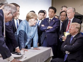 In this photo made available by the German Federal Government, German Chancellor Angela Merkel, center, speaks with U.S. President Donald Trump, seated at right, during the G7 Leaders Summit in La Malbaie, Quebec, Canada, on Saturday, June 9, 2018. (Jesco Denzel/German Federal Government via AP)