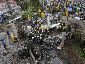 Rescuers stand amid the wreckage of a private chartered plane that crashed in Ghatkopar area, Mumbai, India, Thursday, June 28, 2018. An official said it was not immediately known how many people were on board the aircraft. Five bodies were recovered from the wreckage and rescue work was continuing.