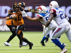 B.C. Lions quarterback Jonathon Jennings, left, fights off Montreal Alouettes' Woody Baron during the second half of a CFL football game in Vancouver, on Saturday June 16, 2018.