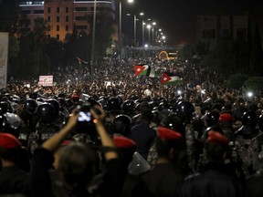 Jordanian protesters shout slogans and raise a national flag during a demonstration outside the Prime Minister's office in the capital Amman late early Monday,  June 4, 2018. (AP Photo/Raad Adayleh)