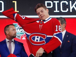 Jesperi Kotkaniemi, of Finland, dons a Carolina Hurricanes jersey after being chose by the team during the NHL hockey draft in Dallas, Friday, June 22, 2018.
