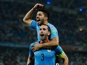 Uruguay's Luis Suarez (top) and Diego Godin celebrate their win over Portugal during the 2018 World Cup round of 16 match at the Fisht Stadium in Sochi, Russia on Saturday, June 30, 2018.
