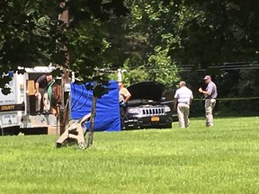 This photo made available by WSLS shows law enforcement surrounding a car that is believed to contain the bodies of a father and child in Raphine, Va., Wednesday, June 6, 2018.