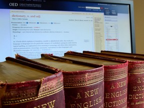 This undated image released by the Oxford English Dictionary shows old volumes of the dictionary next to the a computer monitor displaying a page from the Oxford English Dictionary website. (Oxford English Dictionary via AP)
